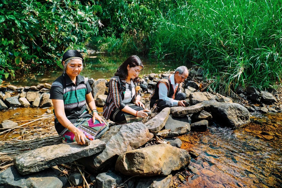Nghệ nhân kiểm tra âm thanh các phiến đá trong thiên nhiên. Ảnh: Bảo tàng Đắk Nông.