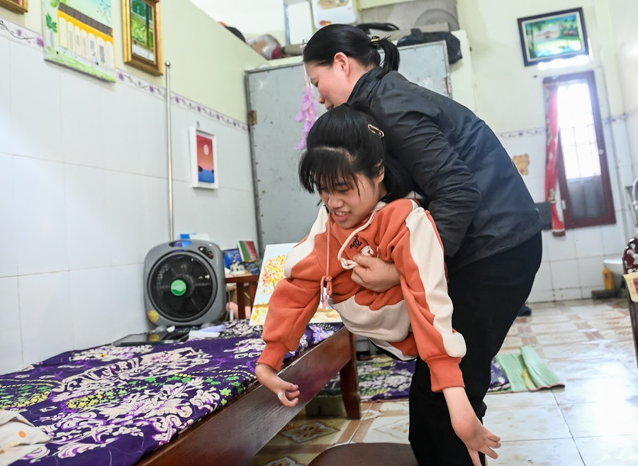 Bị bại liệt bẩm sinh, chân tay Thơm teo nhỏ, nên mọi sinh hoạt phải có người giúp đỡ. co-gai-ve-tranh-bang-mieng-1.jpg