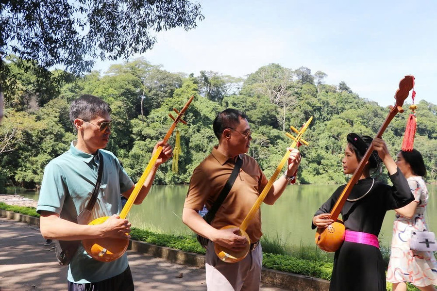 Nhiều du khách được hướng dẫn sử dụng đàn Tính. Ảnh: TTXVN. hon-then-vang-vong-tren-dat-thieng-4.jpg