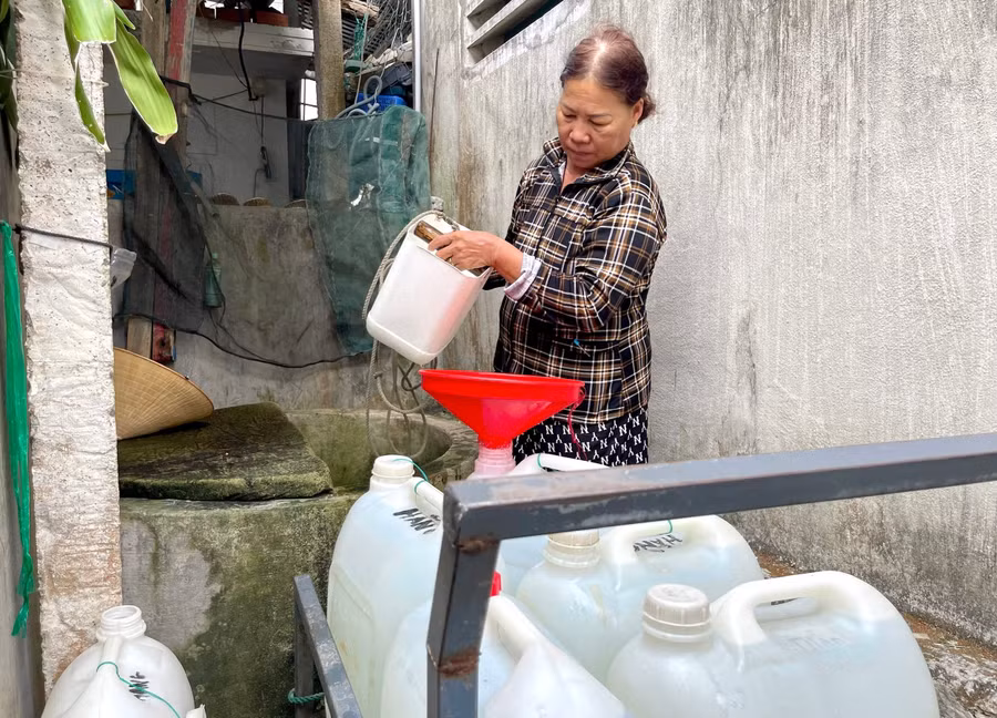 Giữa trưa, bà Trương Thị Hằng mang gàu vét chút nước còn sót lại ở chiếc giếng nước ngọt duy nhất của làng.