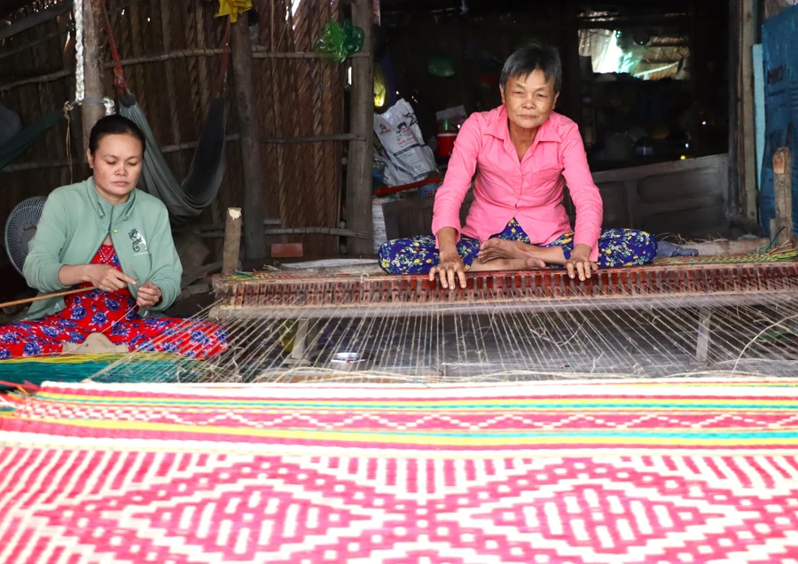 Bà Lê Thị Nhất và con gái đang dệt chiếu. 