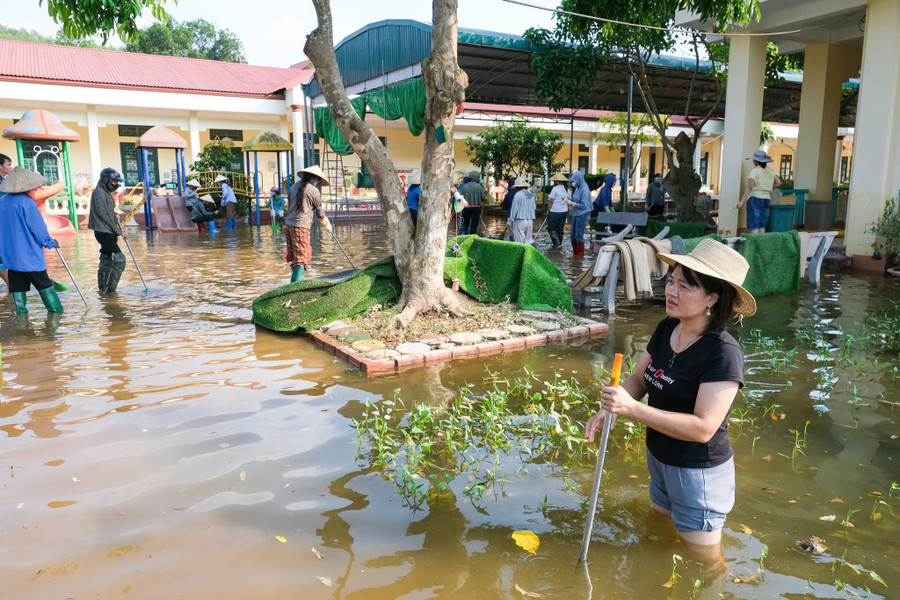 Cô Ninh Thị Thúy Tưởng - Hiệu trưởng Trường Mầm non Tân Thanh, cầm gậy để kiểm tra tình trạng ngập nước trong trường. bac-ninh-tai-thiet-sau-lu-on-dinh-doi-song-7.jpg