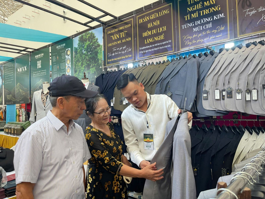 Khách tham dự hội chợ thích thú trải nghiệm sản phẩm của Hợp tác xã may làng nghề Vân Từ (Phú Xuyên, Hà Nội). Ảnh: TTXVN hoi-cho-mua-thu-2025-co-hoi-vang-cho-doanh-nghiep-1.jpg