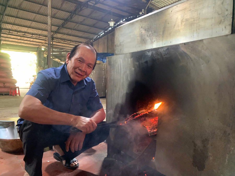 Ông Hoàng Chuẩn bên máy rang hạt điều bằng củi do ông sáng chế. Ảnh: NVCC