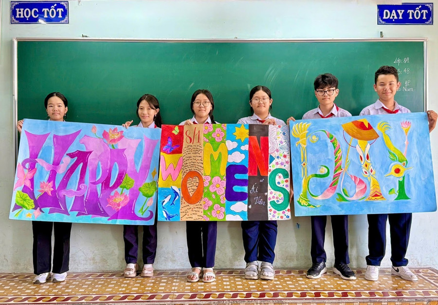 Học sinh chụp ảnh "check-in" bên cạnh những bức tranh trang trí nhiều sắc màu, trong đó có ghi tên mẹ của các học sinh. Ảnh: NVCC