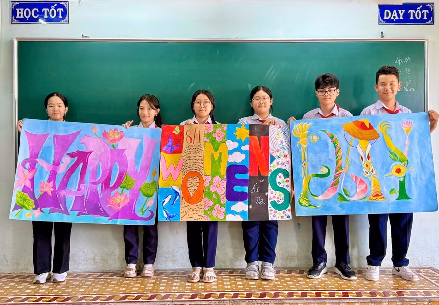 Học sinh chụp ảnh "check-in" bên cạnh những bức tranh trang trí nhiều sắc màu, trong đó có ghi tên mẹ của các học sinh. Ảnh: NVCC