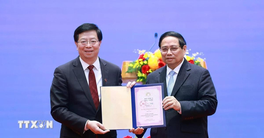 Ông Khưu Dũng, Bí thư Đảng ủy Đại học Thanh Hoa, Trung Quốc trao tặng Thủ tướng Phạm Minh Chính danh hiệu "Giáo sư danh dự Đại học Thanh Hoa". (Ảnh: Dương Giang/TTXVN).