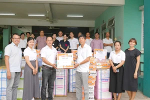 Nhà báo Nguyễn Anh Tú trao quà cho ông Đinh Hữu Tuyến – Giám đốc Trung tâm Bảo trợ trẻ em Tam Bình.