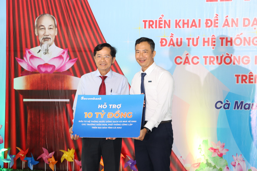 Lãnh đạo Sở GD&ĐT Cà Mau (trái) nhận bảng tượng trưng hỗ trợ 10 tỷ đồng từ lãnh đạo Sacombank thực hiện Đề án đầu tư hệ thống nước uống sạch và nhà vệ sinh trường học. kg-14.jpg