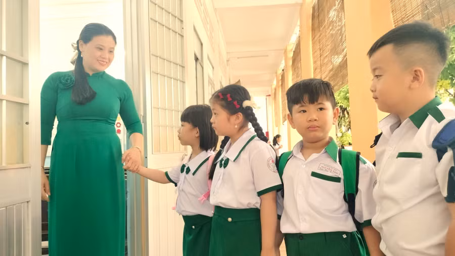 Học sinh được giáo viên chào đón trước cửa lớp.