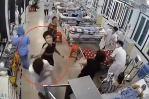 Người đàn ông dùng tay tác động vào vùng đầu, mặt nhân viên y tế. Ảnh cắt từ clip