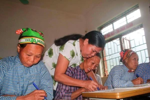 Cô giáo hướng dẫn học viên viết chữ tại lớp xóa mù chữ ở Lũng Chuống, xã Tổng Cọt, tỉnh Cao Bằng. (Ảnh: Chu Hiệu/TTXVN)