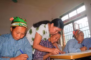 Cô giáo hướng dẫn học viên viết chữ tại lớp xóa mù chữ ở Lũng Chuống, xã Tổng Cọt, tỉnh Cao Bằng. (Ảnh: Chu Hiệu/TTXVN)