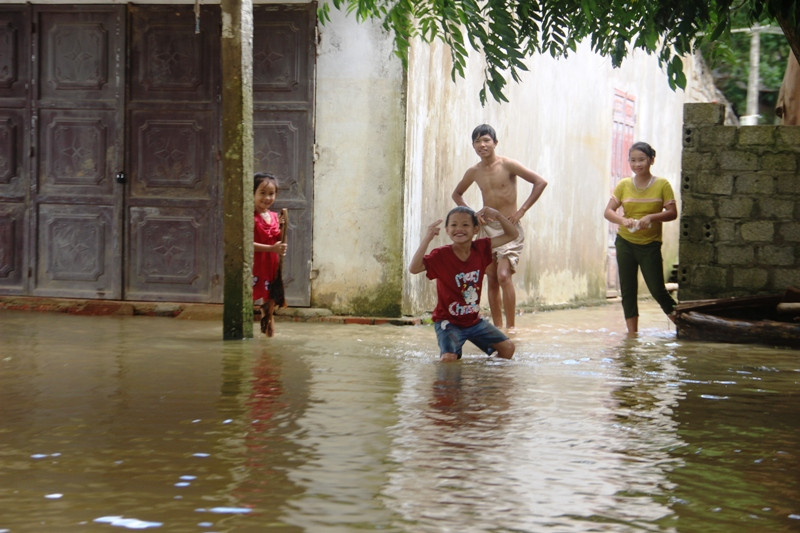 Những đứa trẻ thích thú, đùa nghịch khi nước lũ tràn về.