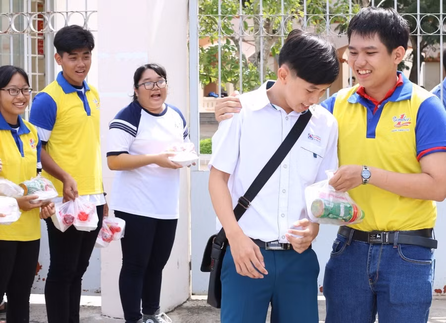 Các tình nguyện viên trao phần cơm trưa cho các thí sinh bên ngoài cổng trường