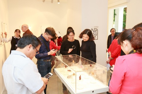 Hoạ sĩ Vũ Kim Thư (người cầm kính lúp ở giữa) tại triển lãm