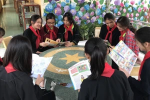 Học sinh đọc sách tại khuôn viên thư viện ngoài trời. Ảnh NT.