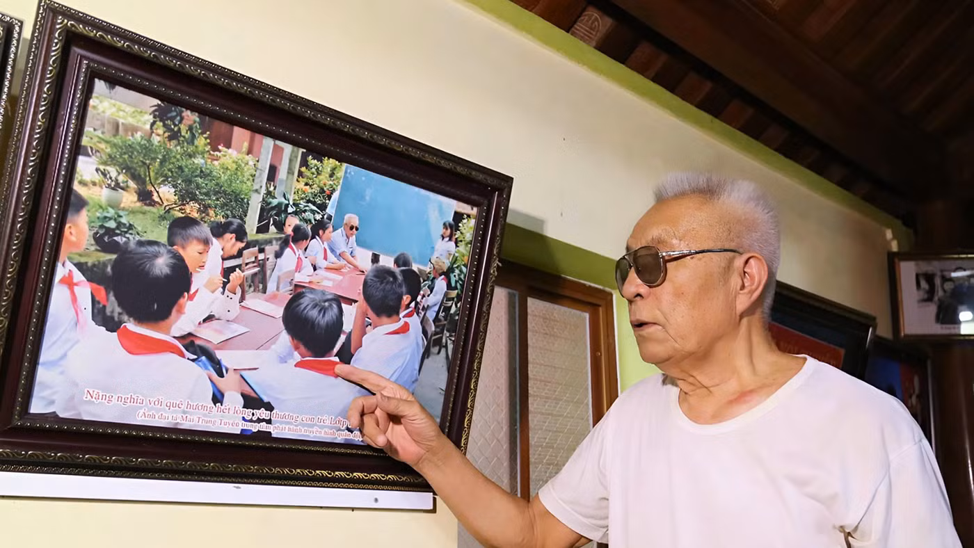 Cựu chiến binh Nguyễn Đăng Khoa bên bức ảnh lưu niệm chụp cùng học trò.