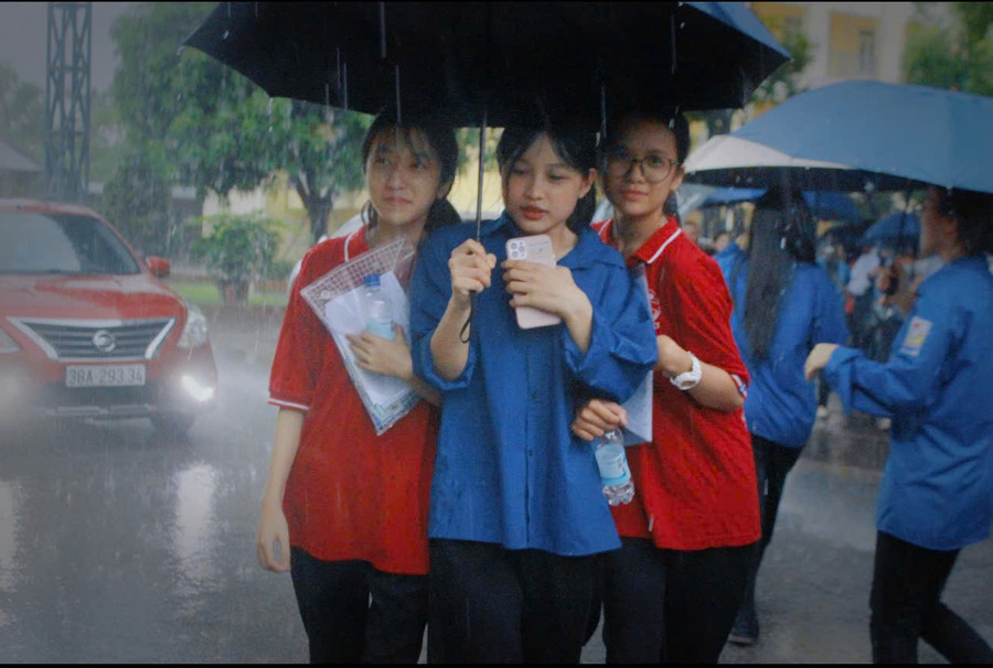 Tình nguyện viên hỗ trợ thí sinh rời điểm thi khi mưa lớn.