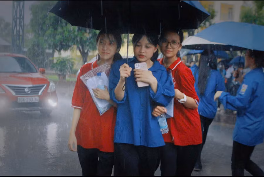 Tình nguyện viên hỗ trợ thí sinh rời điểm thi khi mưa lớn.