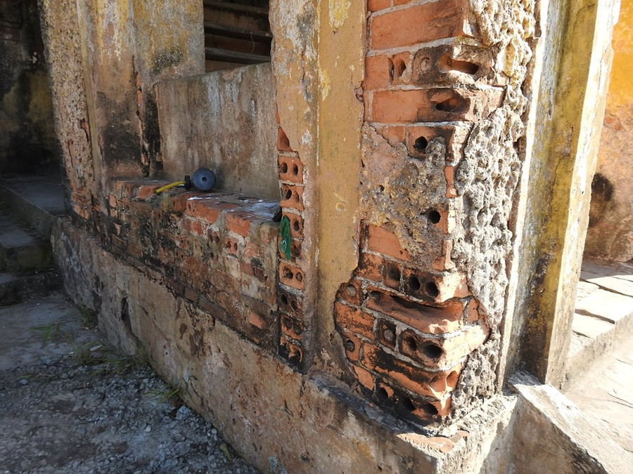 Tường bị bong hết lớp vữa, lộ ra gạch đỏ bên trong. Tường bị bong hết lớp vữa, lộ ra gạch đỏ bên trong.