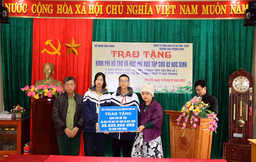 Bà Vũ Kiều Hưng đại diện Công ty TNHH Dịch vụ và Phát triển thương mại Trường Vinh trao tặng kinh phí hỗ trợ học tập cho 2 em học sinh.