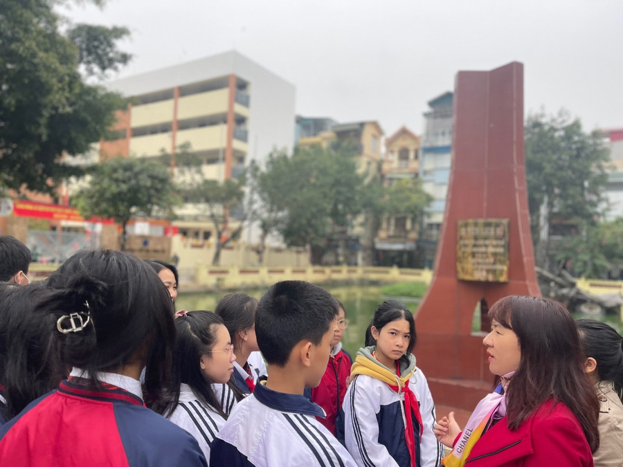 Học sinh lắng nghe cô Trương Châu Giang - Phó Hiệu trưởng nhà trường chia sẻ những dấu ấn về di tích Hồ Hữu Tiệp và trận Điện Biên phủ trên không.