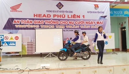 Hướng dẫn học sinh đội mũ bảo hiểm đúng quy cách khi ngồi trên xe máy.