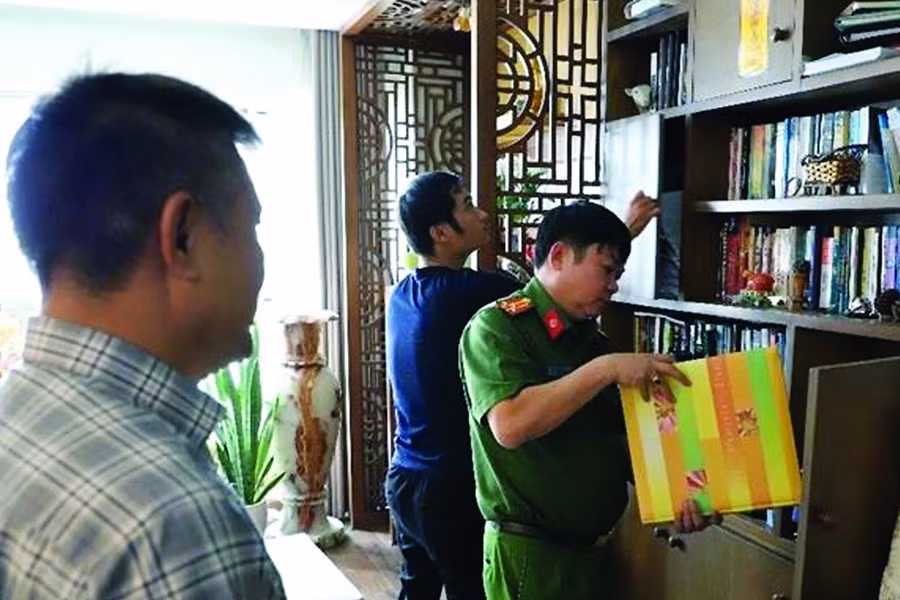 Công an khám xét trước sự chứng kiến của ông Trần Huy Lập (bìa trái).