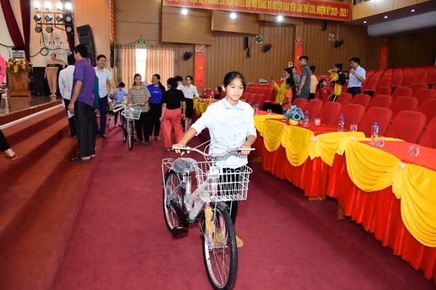 Học sinh nghèo vui mừng bên chiếc xe đạp mới được trao tặng.