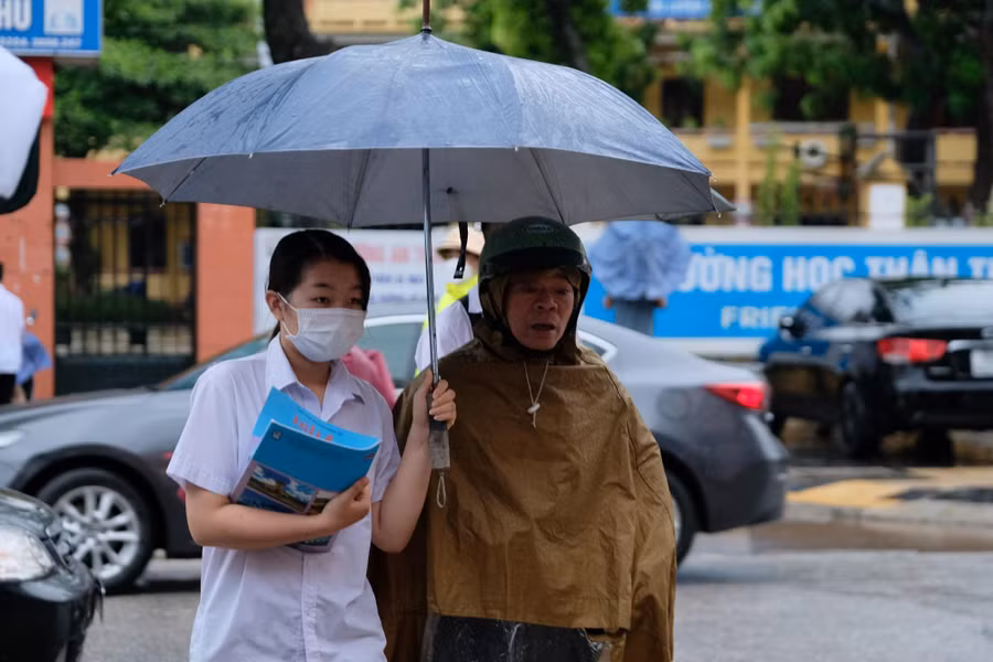 Phụ huynh đưa thí sinh đến Điểm thi trường THPT Ngô Sĩ Liên sớm dưới cơn mưa nặng hạt.