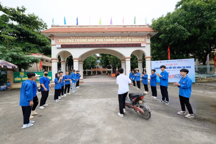 Thí sinh đầu tiên đến Điểm thi trường THPT Nguyễn Văn Cừ chiều 8/7, đi giữa tràng pháo tay động viên thi tốt.