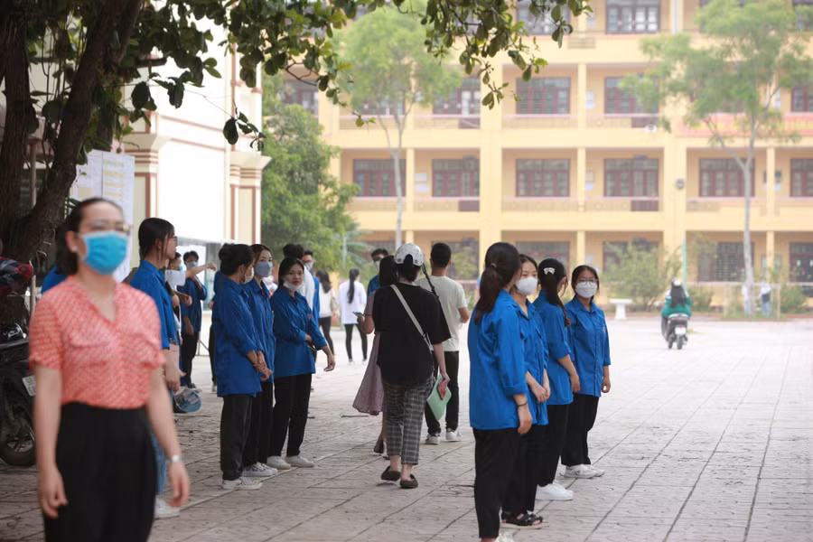 Tình nguyện viên đứng thành nhiều hàng để hướng dẫn thí sinh đến đăng ký dự thi tại Điểm trường THPT Ngô Sĩ Liên (thành phố Bắc Giang).