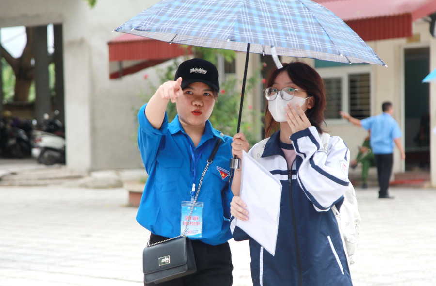 Tình nguyện viên che ô cho thí sinh và hướng dẫn vào phòng thi. Tình nguyện viên che ô cho thí sinh và hướng dẫn vào phòng thi.