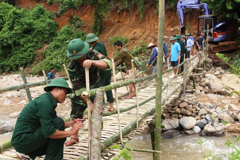 Các chiến sĩ Đội sản xuất số 3, Đoàn Kinh tế Quốc phòng 5 (Quân khu 4) và Bộ đội Biên phòng Đồn Biên phòng Quang Chiểu cùng người dân dựng cầu tạm mở đường vượt suối Sim.