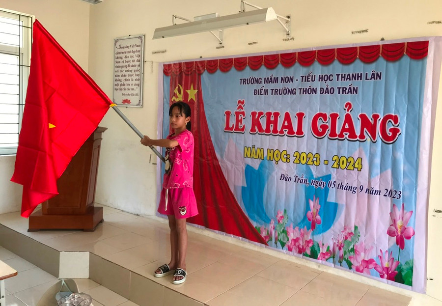 Một em học sinh được phân công nhiệm vụ cầm cờ.