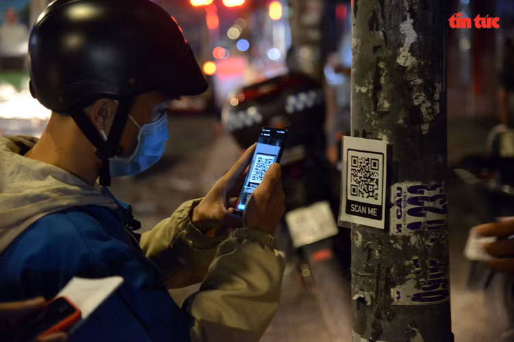 Người dân dùng điện thoại chụp mã code để khai báo y tế điện tử.