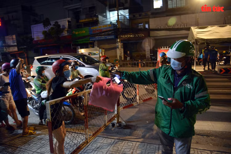 Người dân đứng nhận đồ qua hàng rào.