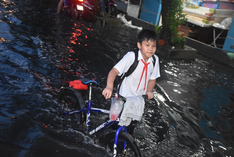 Mặc dù đi xe đạp nhưng cậu học sinh này phải dắt bộ vì nước ngập sâu.