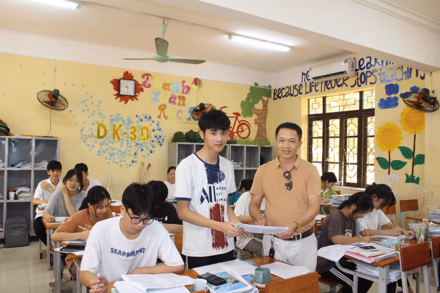 Thầy Trần Quốc Lập trao đổi bài với học sinh lớp ôn tập.