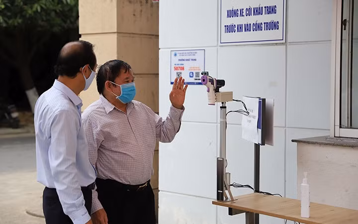 GS.TSKH Bùi Văn Ga (bên phải) kiểm tra máy đo thân nhiệt từ xa tại Trường Đại học Ngoại ngữ -Đại học Đà Nẵng.