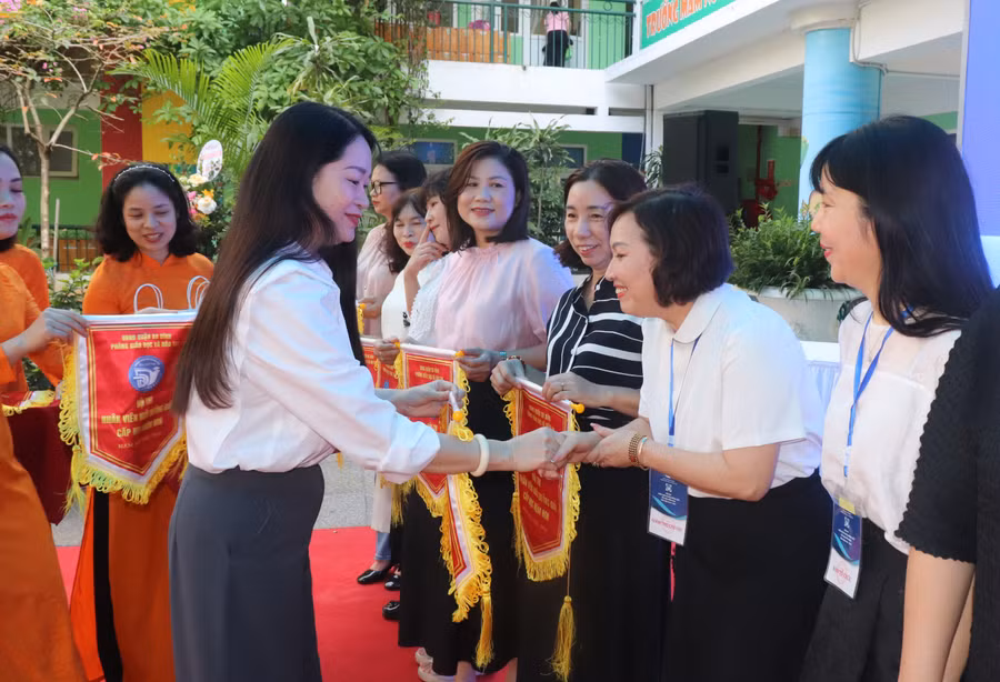Bà Phạm Thị Diễm - Phó Chủ tịch UBND quận Ba Đình (bên trái) trao cờ thi đua cho đại diện các đơn vị tham dự Hội thi.