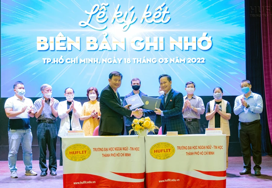 Đại diện HUFLIT và MoMo trao văn bản ký kết.