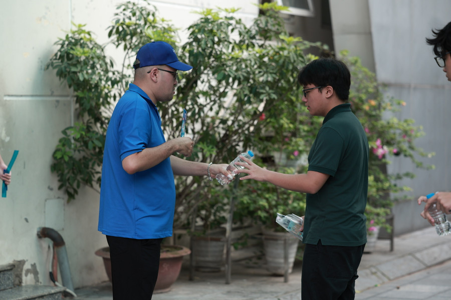 Thanh niên tình nguyện viên tiếp nước cho thí sinh trước khi vào phòng thi tại điểm thi Trường THCS Dịch Vọng.