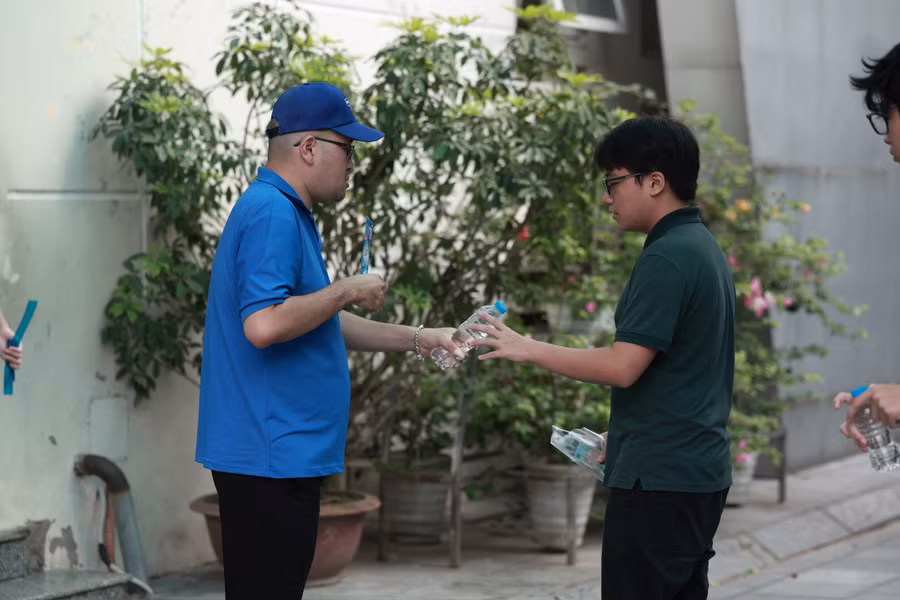 Thanh niên tình nguyện viên tiếp nước cho thí sinh trước khi vào phòng thi tại điểm thi Trường THCS Dịch Vọng.