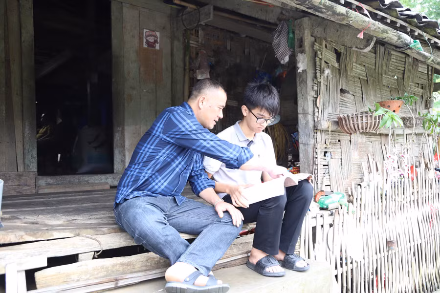 Đến nhà trò trời vẫn mưa, thầy Hà Văn Diễn – giáo viên Trường Tiểu học và THCS 1 An Sơn tranh thủ ôn lại bài cùng học sinh. Ảnh NC.