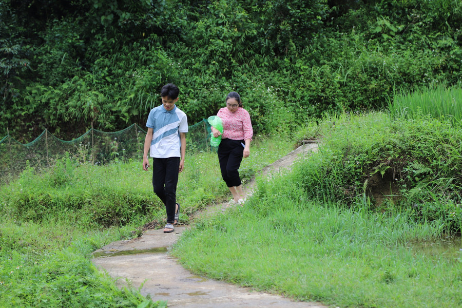 Do nhà học sinh sâu trong núi, cô Hoàng Phương Lan phải gửi xe ở đường lớn đi bộ hơn 2 km để đón trò. Ảnh NC.