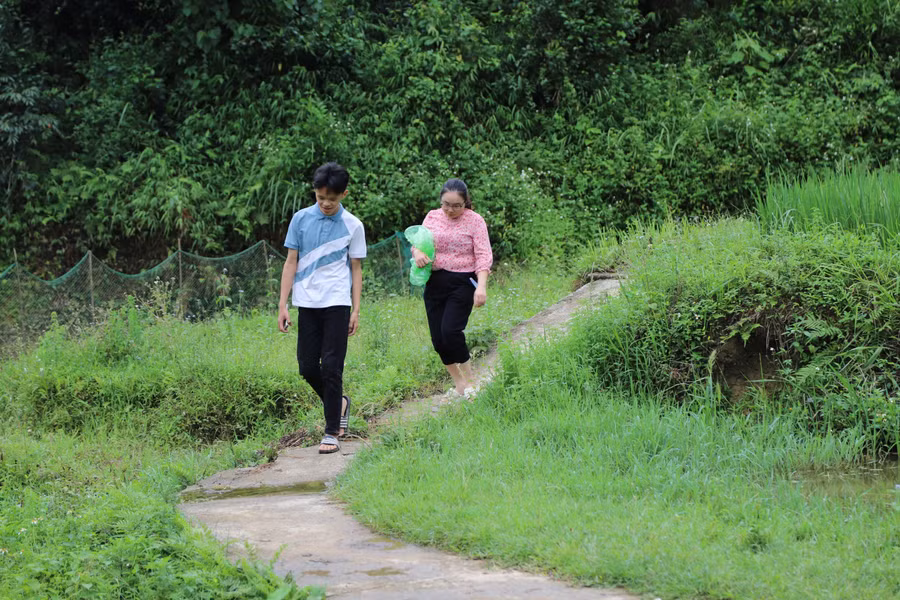 Do nhà học sinh sâu trong núi, cô Hoàng Phương Lan phải gửi xe ở đường lớn đi bộ hơn 2 km để đón trò. Ảnh NC.
