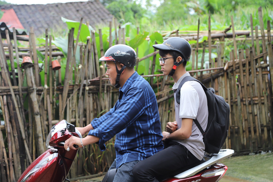 Tạnh mưa, thầy Hà Văn Diễn cùng trò di chuyển đến điểm thi. Ảnh NC.