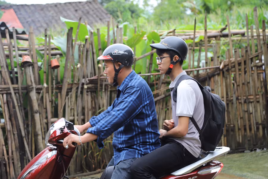 Tạnh mưa, thầy Hà Văn Diễn cùng trò di chuyển đến điểm thi. Ảnh NC.